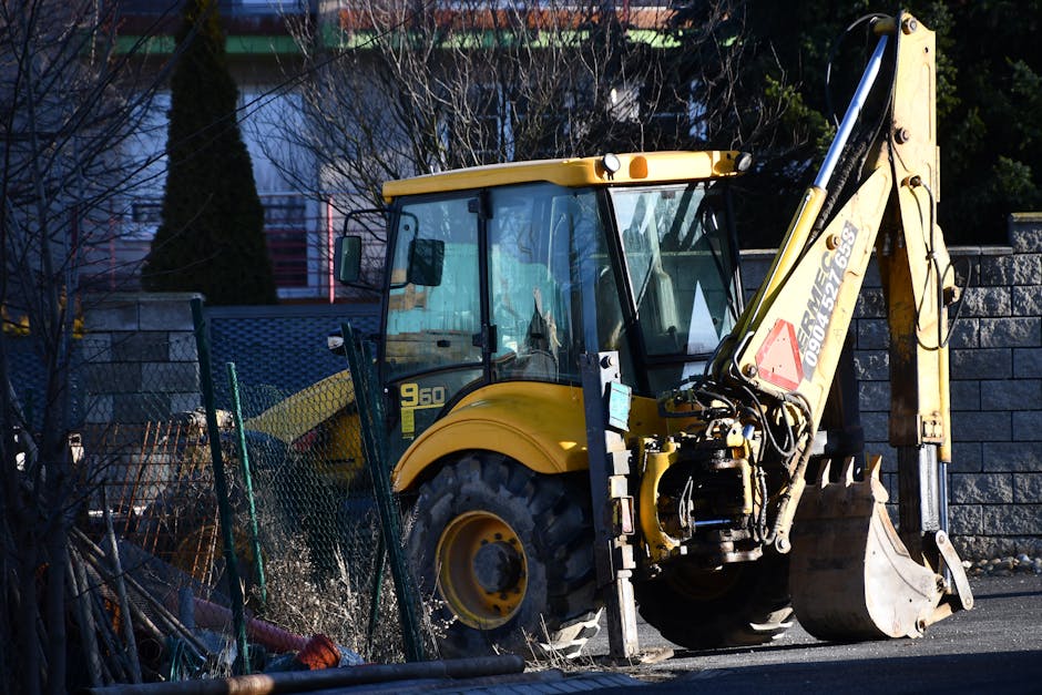 A yellow excavator rests on an urban construction site during daylight. - kaivinkoneenkuljettajan palkka suomessa